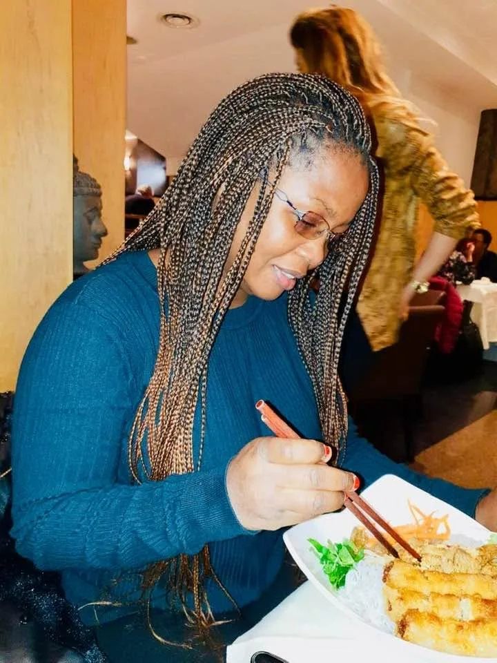 Marie-Thècle Amani assise dans un espace intérieur, un carnet ouvert devant elle.